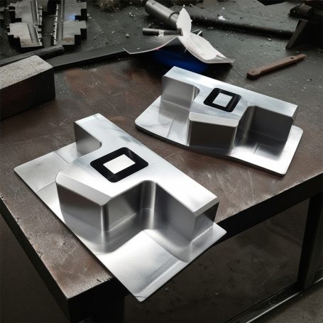 Dos piezas de metal pulido en una superficie de trabajo.