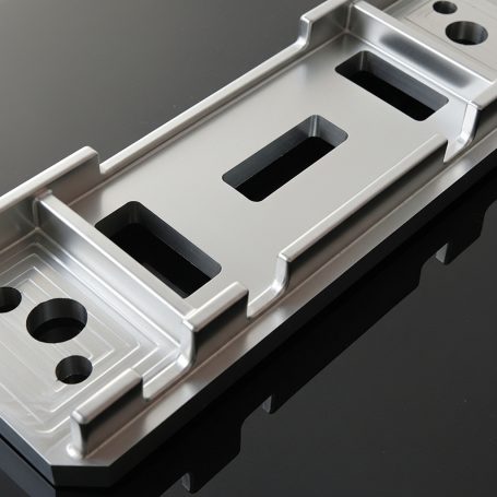 Placa metálica pulida con orificios y ranuras para ensamblaje.