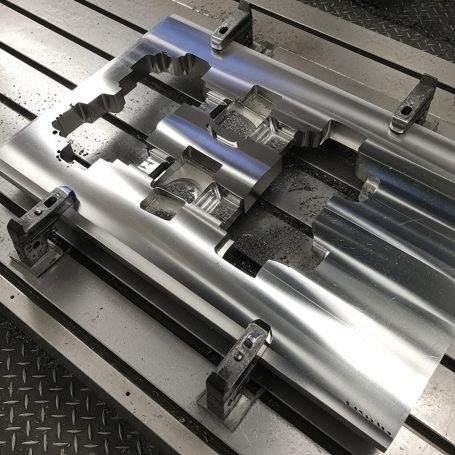 Placa metálica con cortes y detalles, sostenida en una superficie de trabajo.